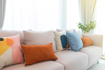 Cozy white sofa with colorful suede pillows in modern living room.