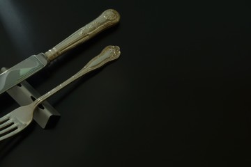lay out antique expensive silver cutlery. knife , fork on the table .  to shine in light. Top view photo of black background with copy space.
