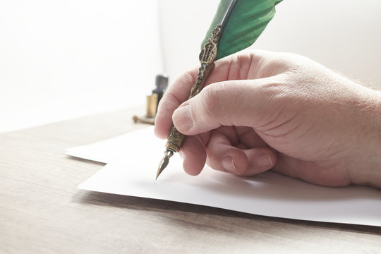 Hand of a man writing a letter or note with a pen and black ink.