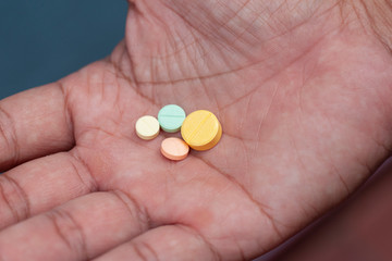 Closeup medicine pills of various sizes in the hands of the patient.