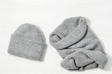 Woolen knitted clothing, wool cap and scarf. Warm womans winter clothes on white wooden background. Top view. Copy space. Flat lay.