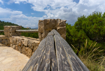 Selective focus shot of a wooden railing connected to a brick post
