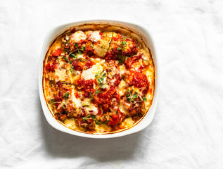 Zucchini cannelloni stuffed with meat with tomato sauce and mozzarella cheese on a light background, top view
