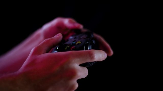 Playing video games in a darkened room with a black background close up on a controller buttons playing slowly for e sports
