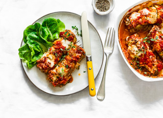 Baked zucchini cannelloni meat filling with tomato sauce, thyme and mozzarella cheese on a light background, top view