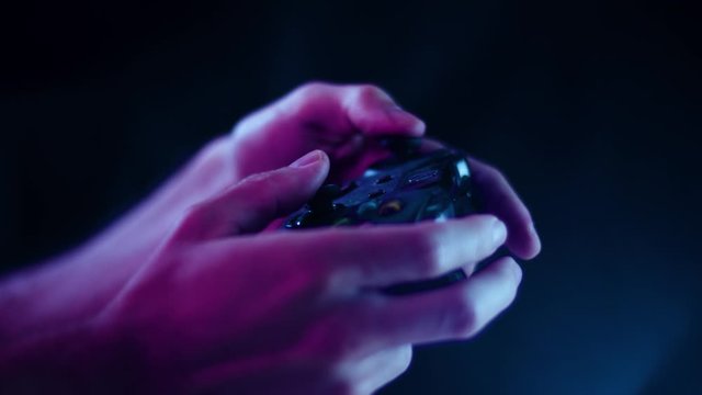 Playing video games in a darkened room with a black background close up on a controller joystick playing quickly blue lens flare for e sports