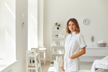 Smiling woman cosmetologist or dermatologist standing and looking at camera in beauty spa salon - obrazy, fototapety, plakaty
