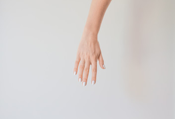  Female hand with a beautiful manicure on a background of a white wall. Delicate and healthy skin on the hands, rejuvenation of the skin of the hands, moisturizing and care