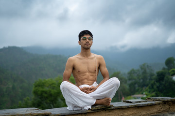 Naklejka na ściany i meble a man practicing meditation and zen energy yoga in mountains.Man doing fitness exercise sport outdoors in morning. Healthy lifestyle concept