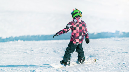 Fototapeta na wymiar Child Snowboarding in the Mountains