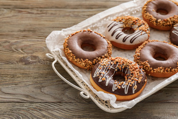 Tray with tasty donuts on table