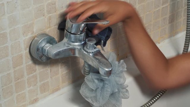 Woman's naked arm turning off hot water bathtub faucet in the bathroom. Close shot pushing the tap.