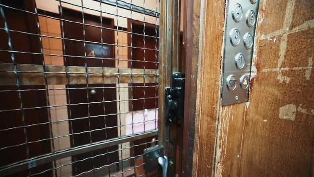 Closing door of an old stylish elevator with wooden sliding gate in residential building. POV interior view