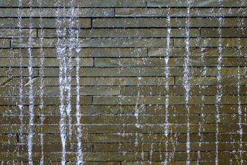 Water feature as a background, water running down a stone brick wall
