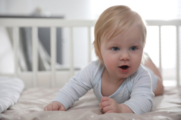 Adorable little baby lying in comfortable crib