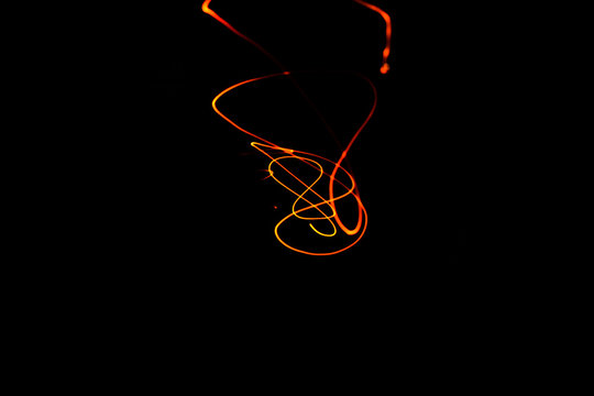 Creative Conceptual Fine Art Photography Motion Blur Sparkle Light Trail On Dark Background Copy Space For Text. Artistic design by lamp fire flame line at night slow shutter speed of camera exposure.