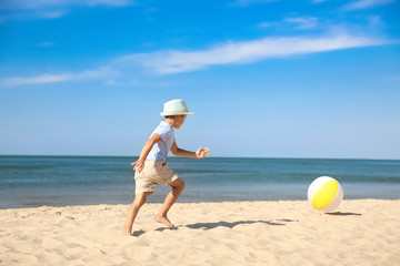 Fototapeta na wymiar Cute little boy playing with inflatable ball on sandy beach