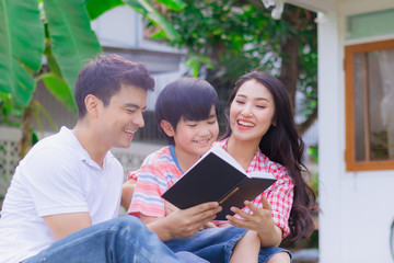 Happy family reading book as activity together in yard at home