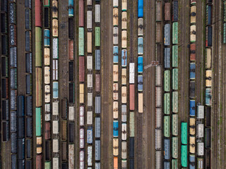 Cargo trains close-up. Aerial view of colorful freight trains on the railway station. Wagons with goods on railroad. Heavy industry. Industrial conceptual scene with trains.