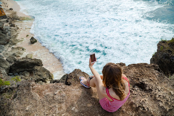 Woman tourist takign photos with her smartphone at a vacation on tropical island.