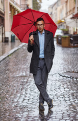 Man holding a red umbrella outdoors.