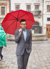 Man holding a red umbrella outdoors.
