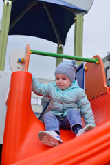 Fototapeta na wymiar Girl rolls down the hill at the playground