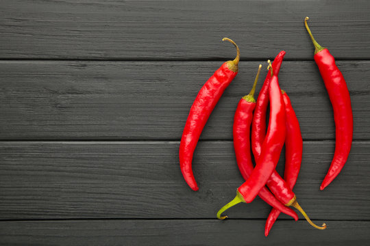Red Hot chili peppers on black wooden background, closeup