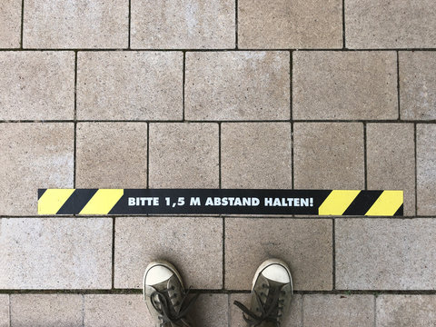 Bitte 1,5 m Abstand halten - German for Please keep 1.5 m distance - line marking on sidewalk - social distancing in Germany