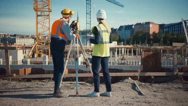Construction Worker Using Theodolite Surveying Optical Instrument for Measuring Angles in Horizontal and Vertical Planes on Construction Site. Engineer and Architect Using Tablet Next to Surveyor.