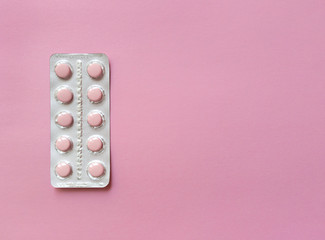 A blister of soft pink pills on pink background. Monochrome simple flat lay with pastel texture with copy space. Medical concept. Stock photo.
