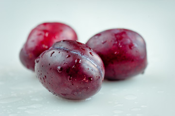Red plum with water drops  on white background