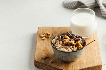 Oatmeal porridge with nuts, chocolate in a gray bowl, a glass of milk. Breakfast, healthy food.Copy space. Good morning.