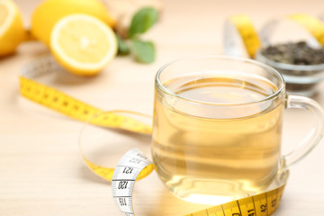 Diet herbal tea and measuring tape on table, closeup. Space for text