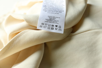 Clothing label with care instructions on beige garment, closeup