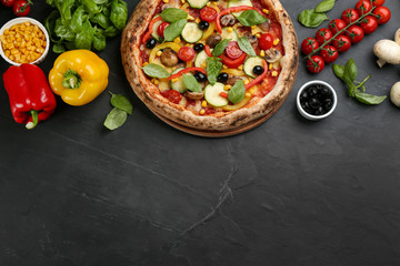 Flat lay composition with delicious hot vegetable pizza on black table. Space for text