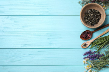 Flat lay composition with healing herbs on light blue wooden table. Space for text