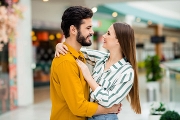 Profile side photo of positive gentle cute spouses girl husband hug cuddle enjoy valentine day rest relax wear yellow striped shirt in shopping mall center store