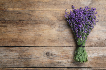 Beautiful lavender bouquet on wooden background, top view. Space for text