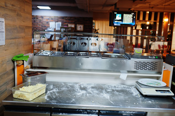 Female chef preparing pizza in restaurant kitchen.