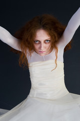 Fototapeta premium An image for halloween, a red-haired woman in the image of a witch in a white outfit with a pale deathly face