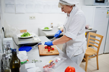 Female chef preparing salad in italian restaurant kitchen.