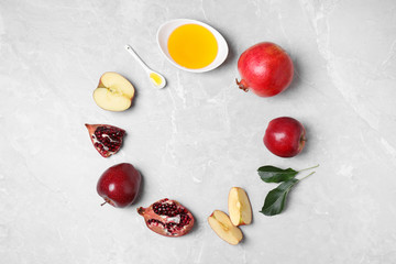 Frame of honey, apples and pomegranates on marble table, flat lay with space for text. Rosh Hashanah holiday