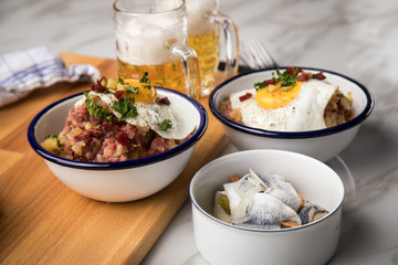 Norddeutscher Hamburger Labskaus mit Rindfleisch Corned Beef, Rote Beete, Kartoffeln, Saure Gurken, Spiegelei, Rollmops und Bier auf Marmor