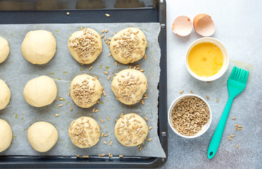 Pieces of raw dough on a pan, silicone brush, egg, seeds. Cooking homemade buns. Top view