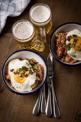 Norddeutscher Hamburger Labskaus mit Rindfleisch Corned Beef, Rote Beete, Kartoffeln, Saure Gurken, Spiegelei, Rollmops und Bier auf Holztisch
