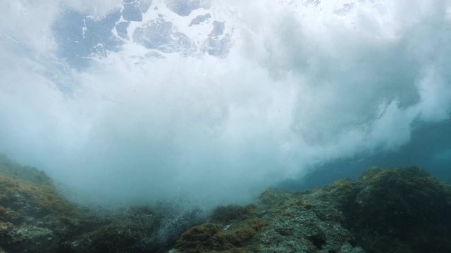 Underwater sea wave breaking on rock below water surface, Mediterranean sea