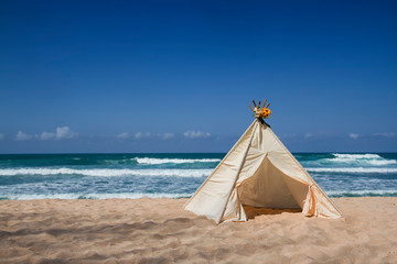 teepee tent with flower on top on the beach