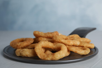 Slate plate with fried onion rings on grey table