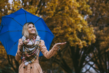 Attractive blonde woman in autumn park in beige coat